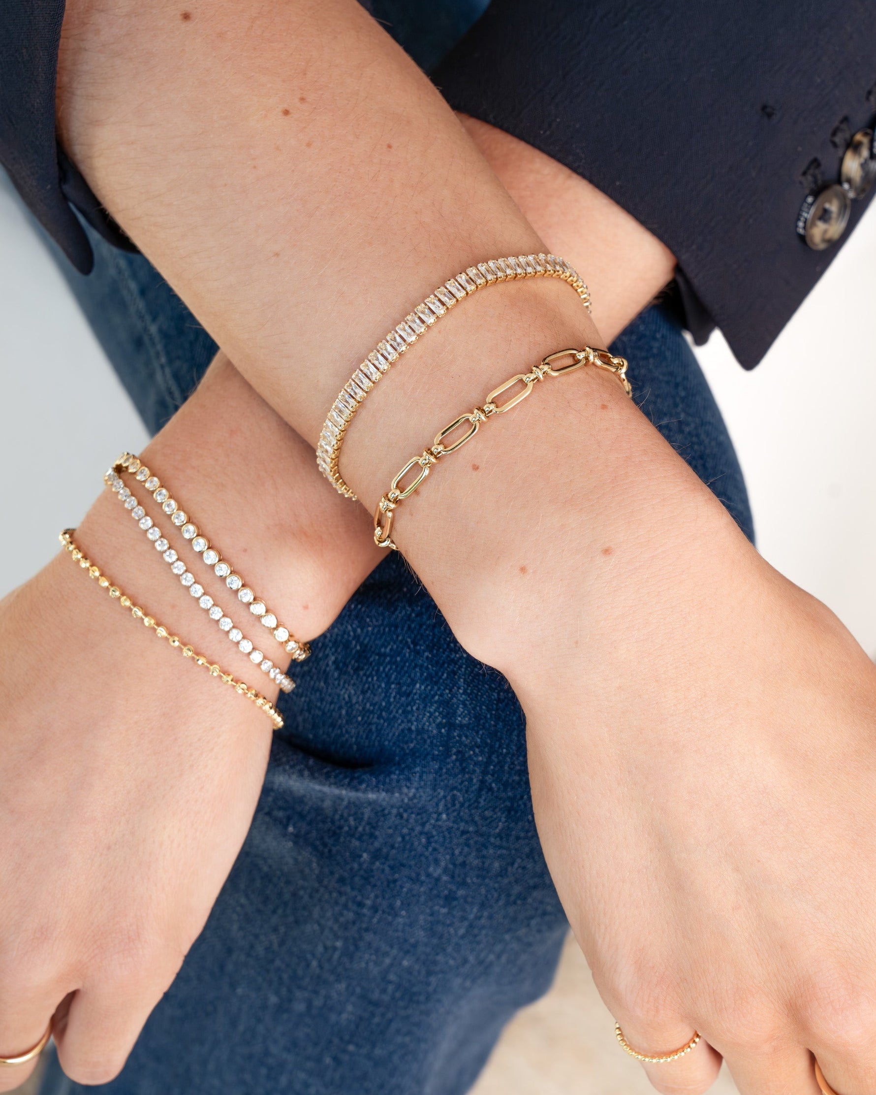 Gold Sami Jewels Baguette Tennis Bracelet stacked with multiple narrow, rectangular-cut gemstones on a delicate bracelet chain.