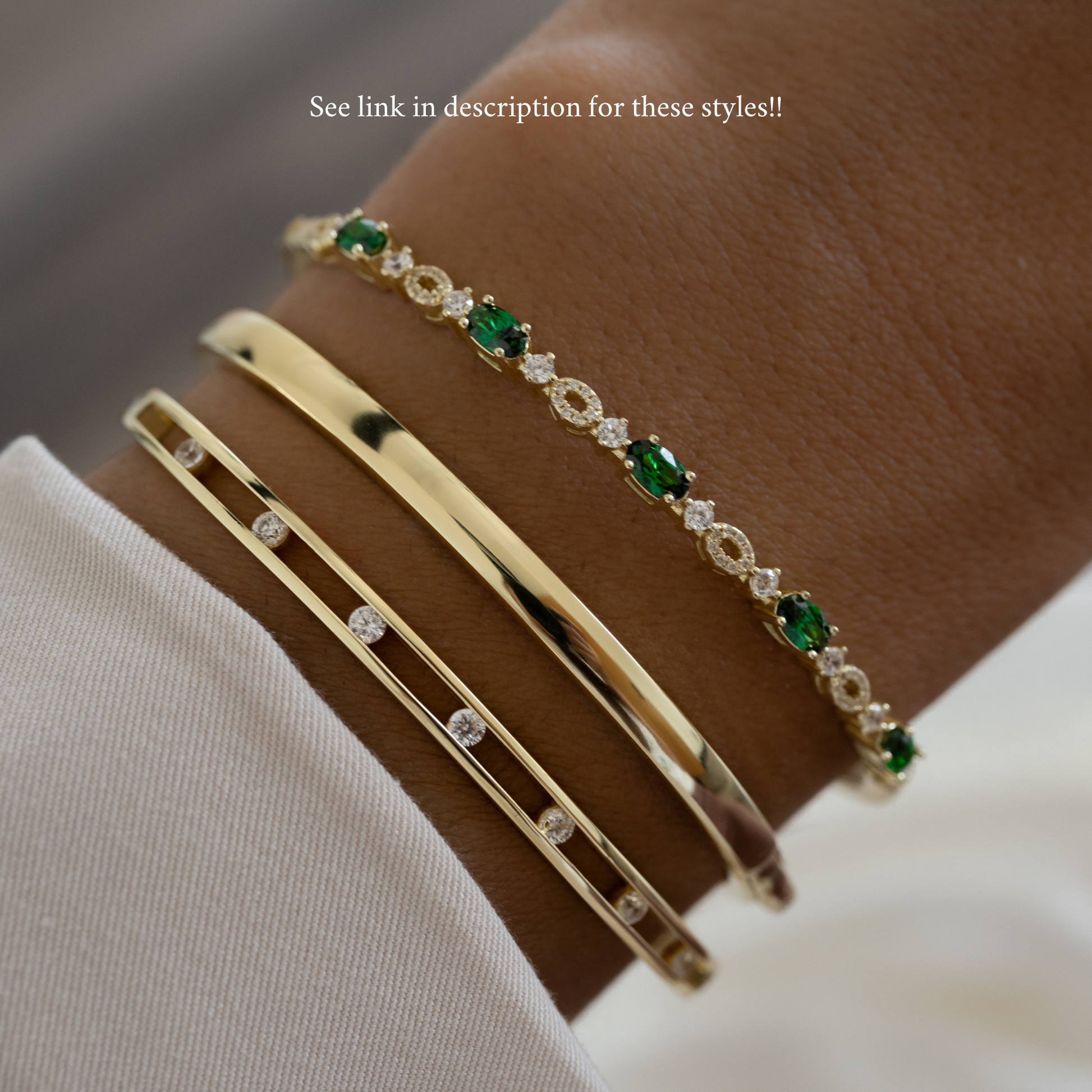 three bangle bracelets stacked together consisting of an emerald bangle a solid bangle and a diamond studded bangle