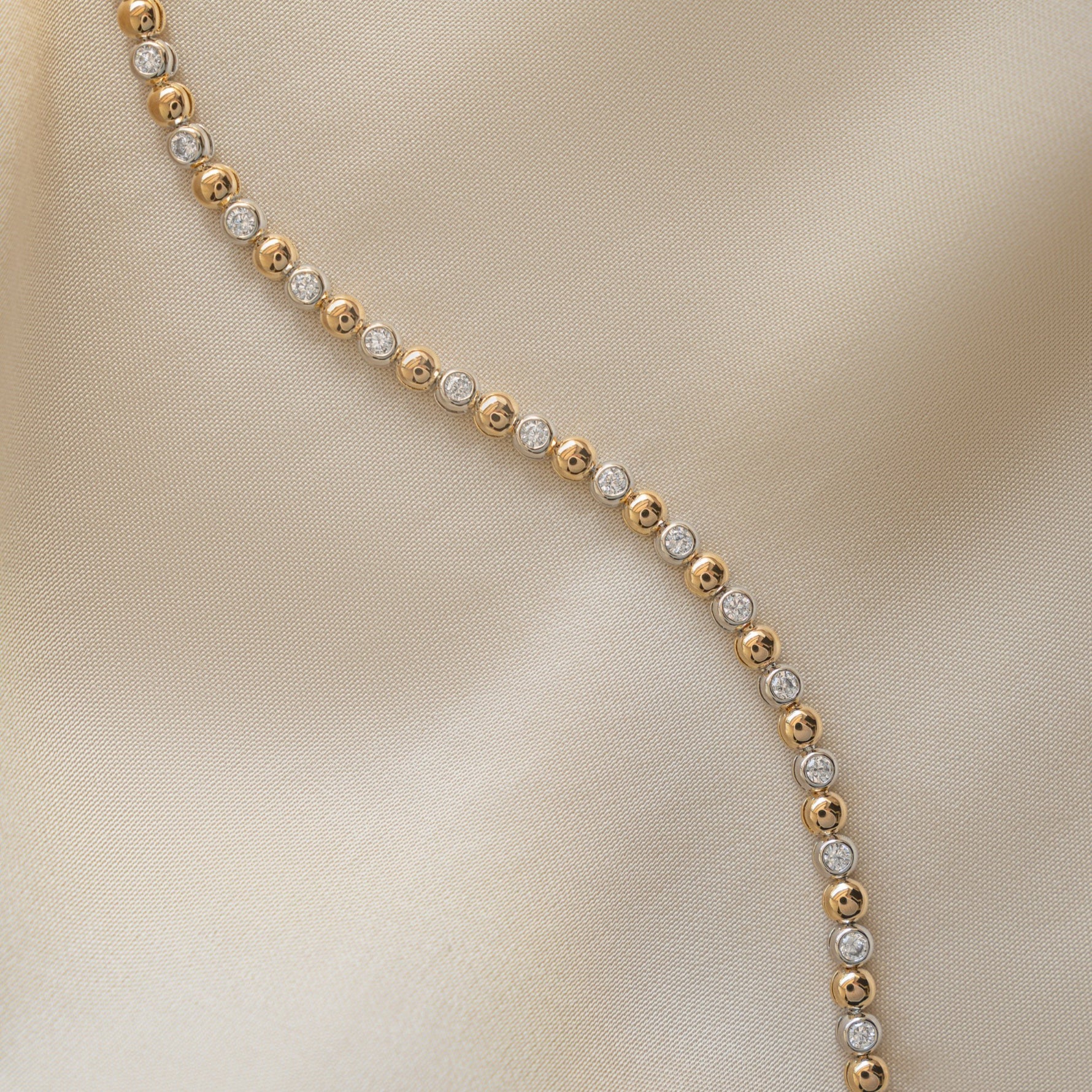 Flat lay of a handmade bracelet with beads and bezel diamonds in gold.