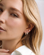 Gold Bezel 3 Stone Huggie Hoop Earrings by Sami Jewels, featuring small, rounded stones set in a sleek hoop design.