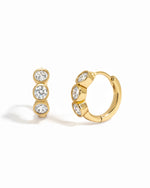 Gold Bezel 3 Stone Huggie Hoop Earrings by Sami Jewels, featuring three sparkling stones on small hoop earrings.