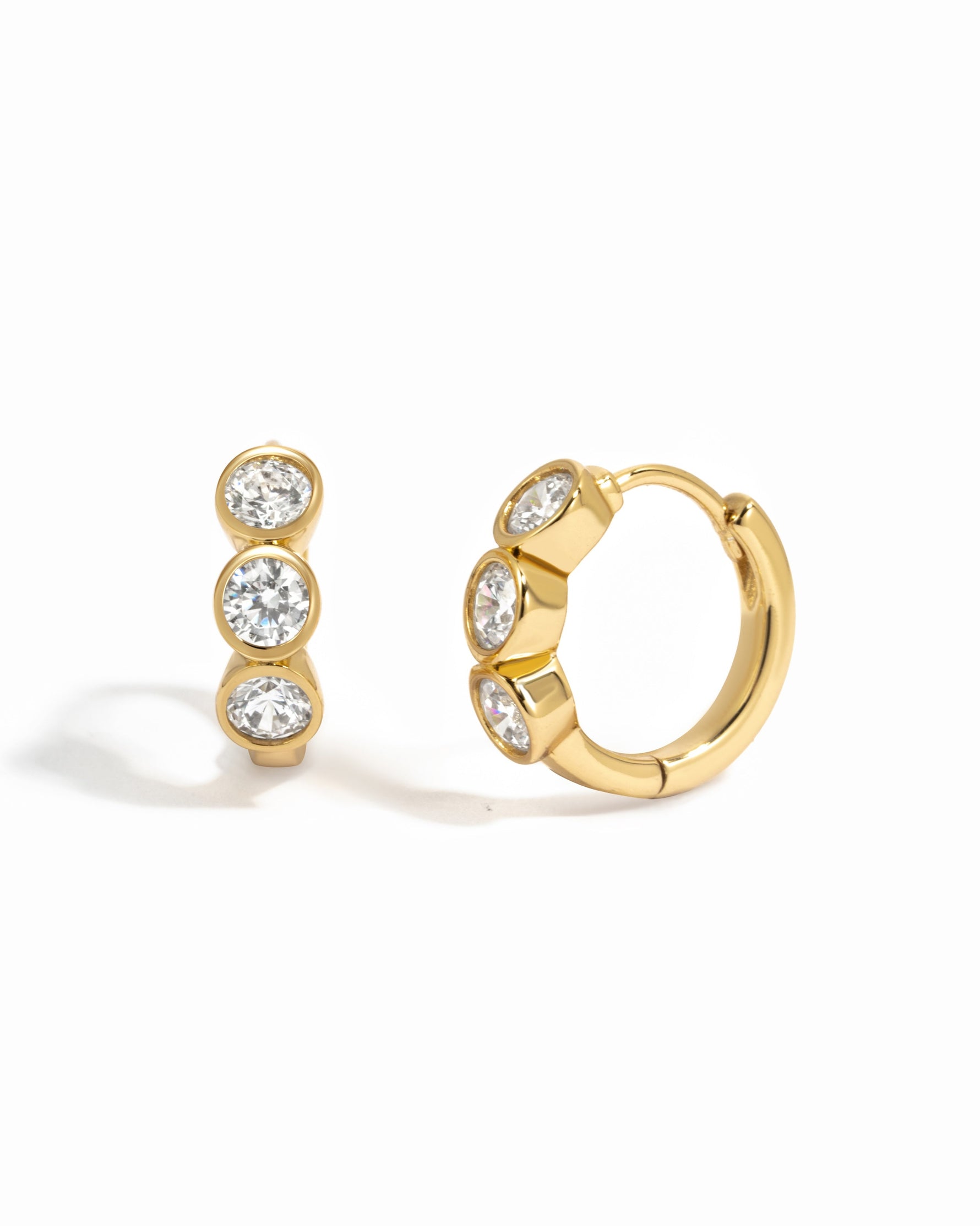 Gold Bezel 3 Stone Huggie Hoop Earrings by Sami Jewels, featuring three sparkling stones on small hoop earrings.