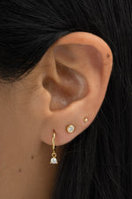 Gold bezel charm huggie earrings by Sami Jewels featuring small, round, open hoop design with decorative charm accents.