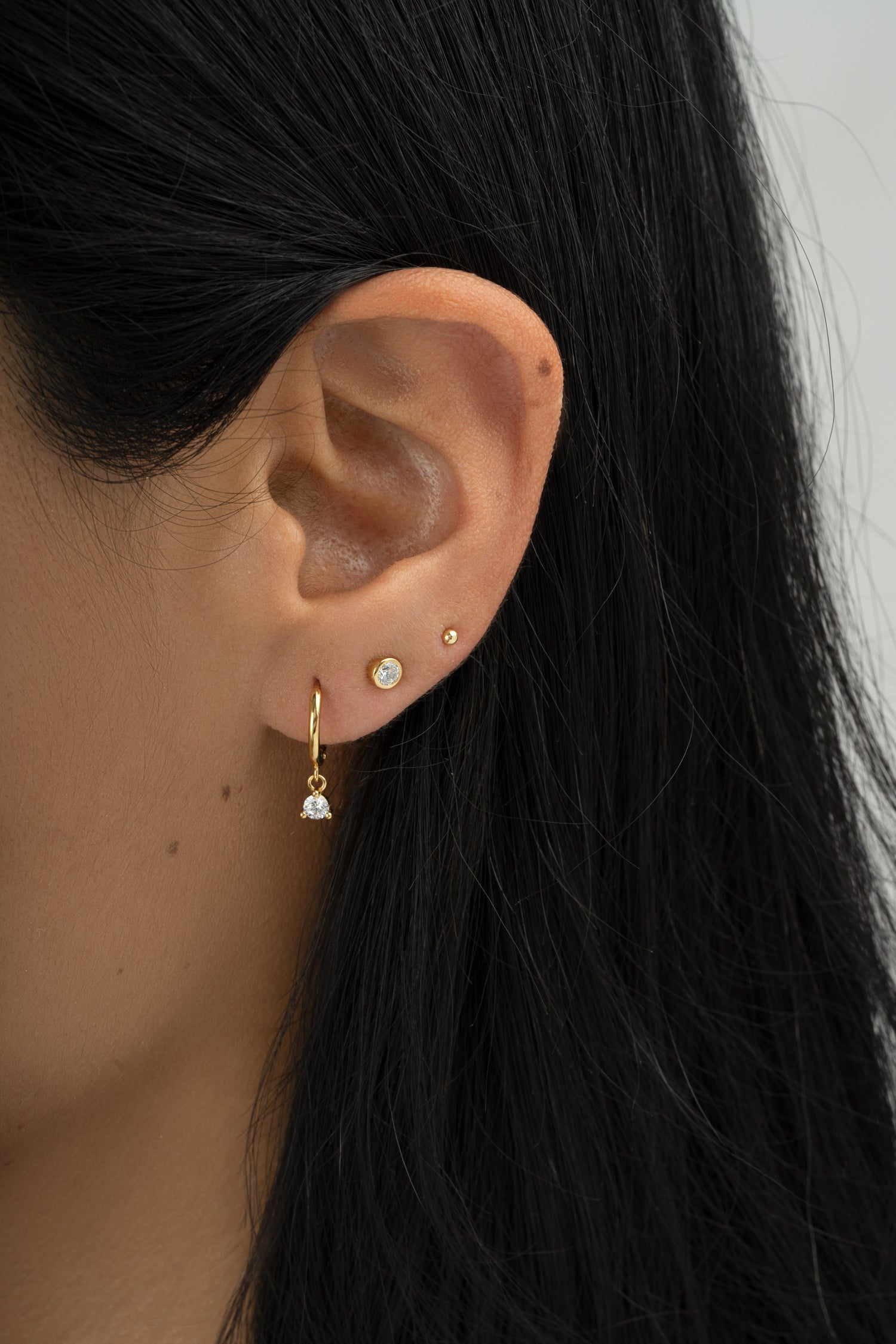Gold bezel charm huggie earrings by Sami Jewels featuring small decorative charms on classic hoop earrings.