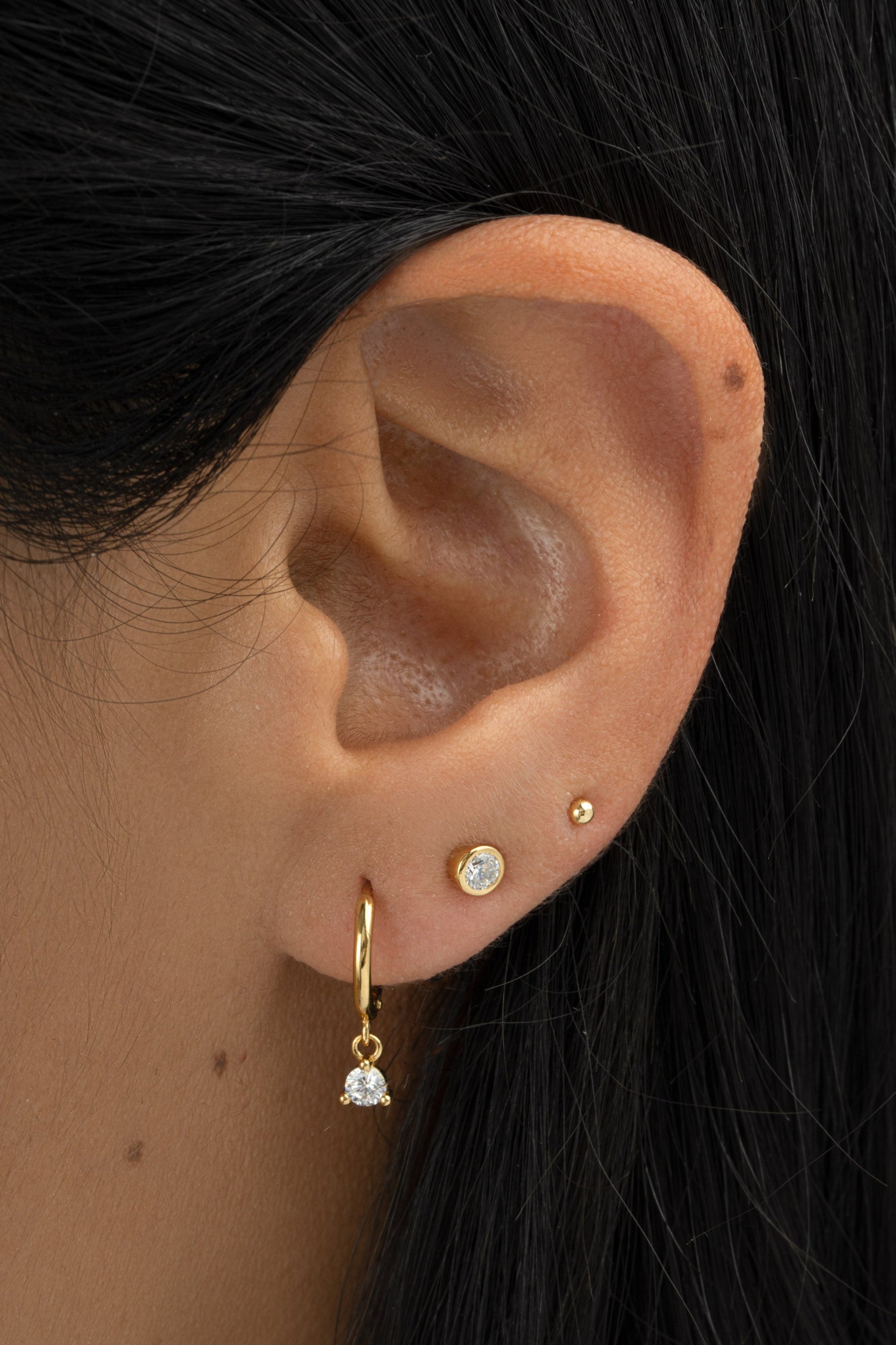 Gold bezel charm huggie earrings by Sami Jewels featuring small, round, open hoop design with decorative charm accents.