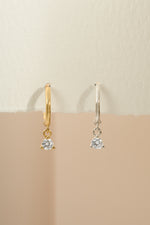 Gold and sterling silver bezel charm huggie earrings by Sami Jewels featuring small hoop design with decorative charms.