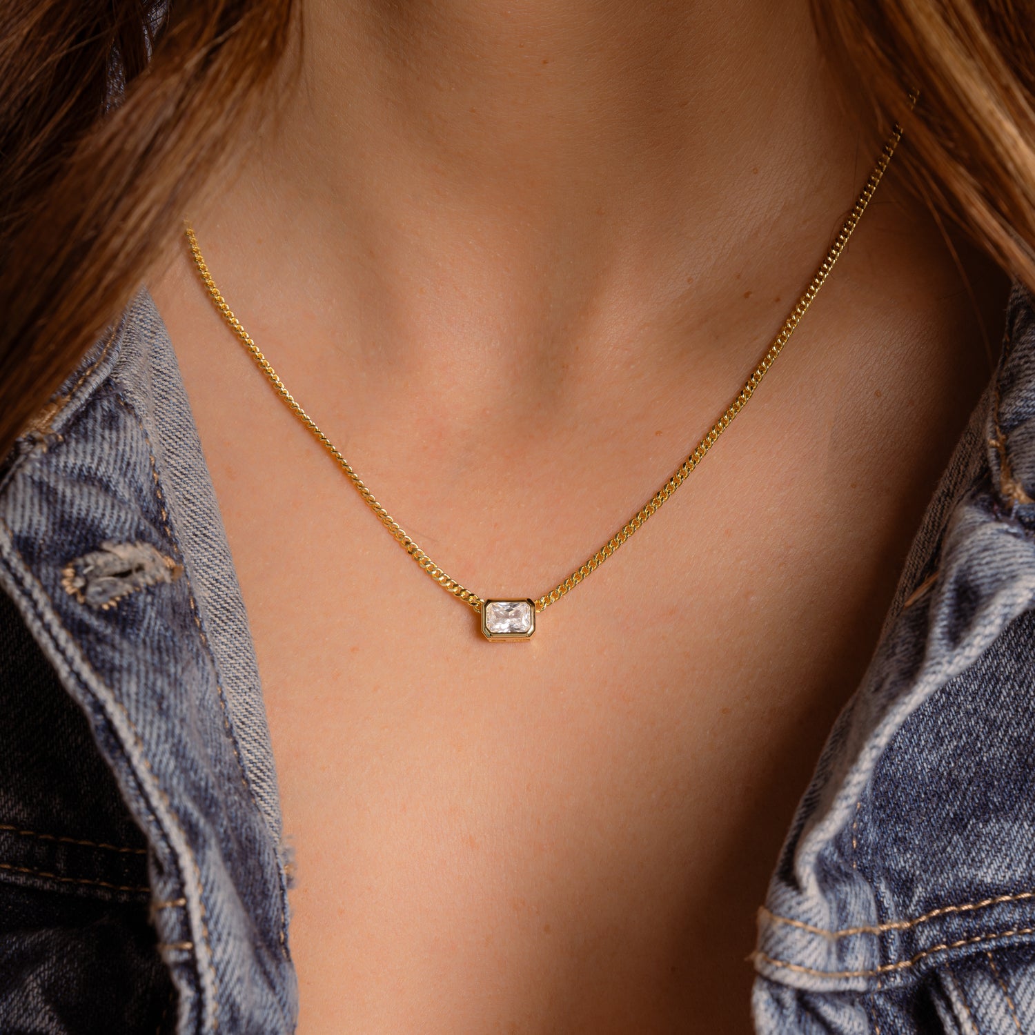 Gold Cuban Chain draping smoothly around model’s neck, Emerald Cut Pendant adding a refined sparkle.