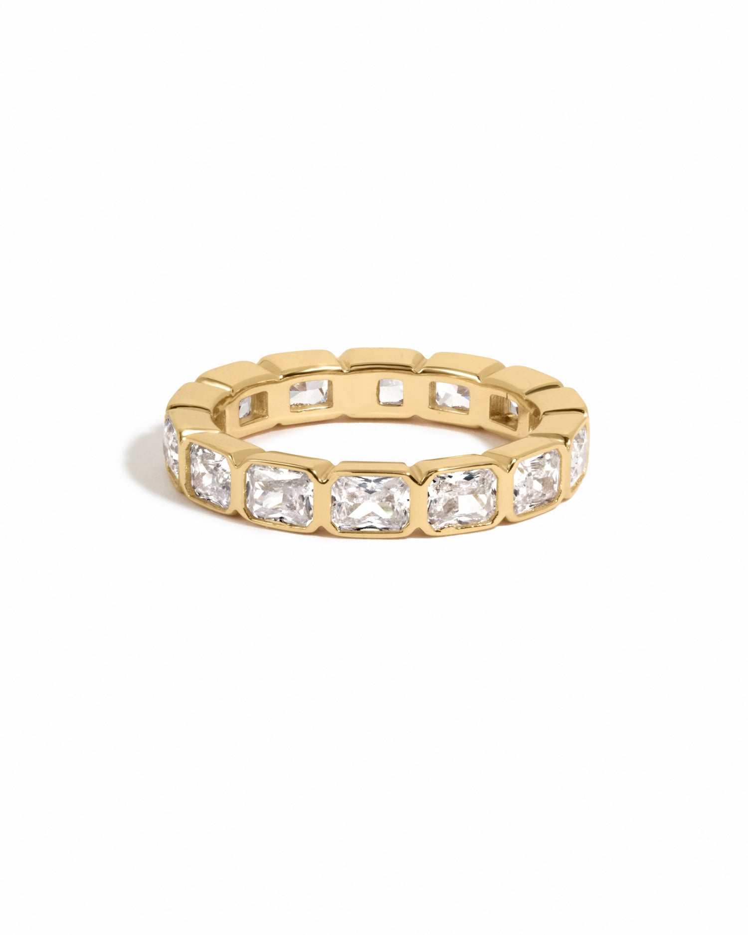 Gold bezel emerald cut eternity band ring from Sami Jewels on a white background.