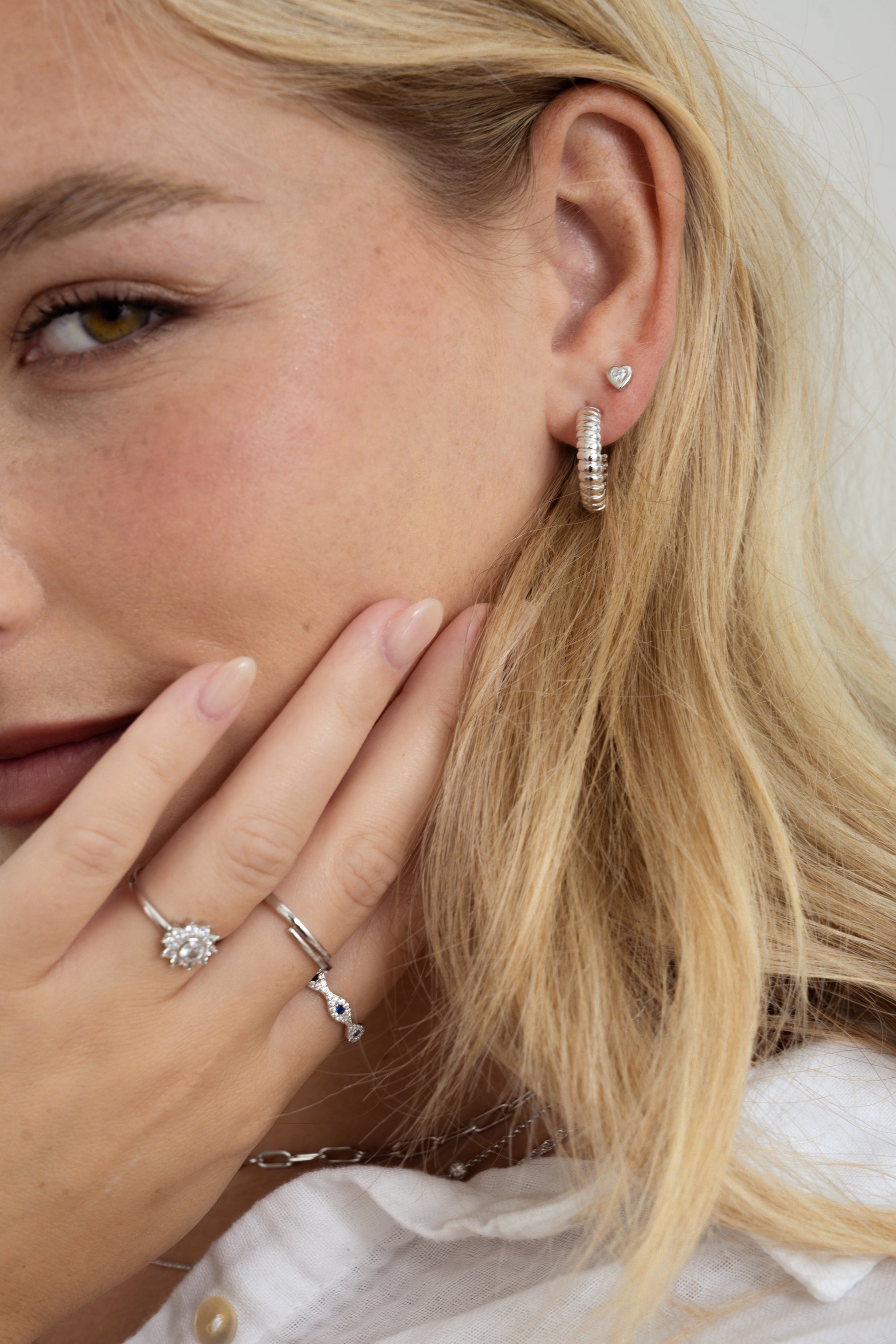 Sterling silver bezel heart stud earrings by Sami Jewels shown on a model, featuring a delicate heart-shaped design.
