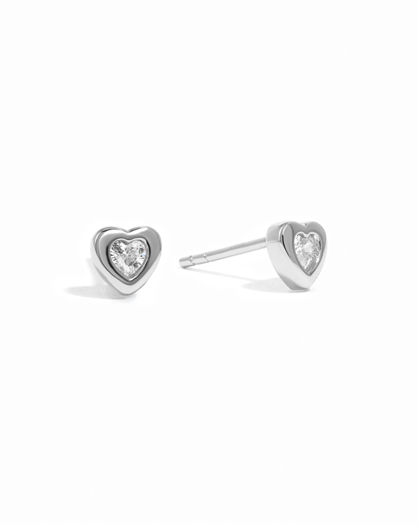 Sterling silver bezel heart stud earrings from Sami Jewels displayed on a white background.