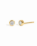 Gold stud earrings with clear gemstones on a white background