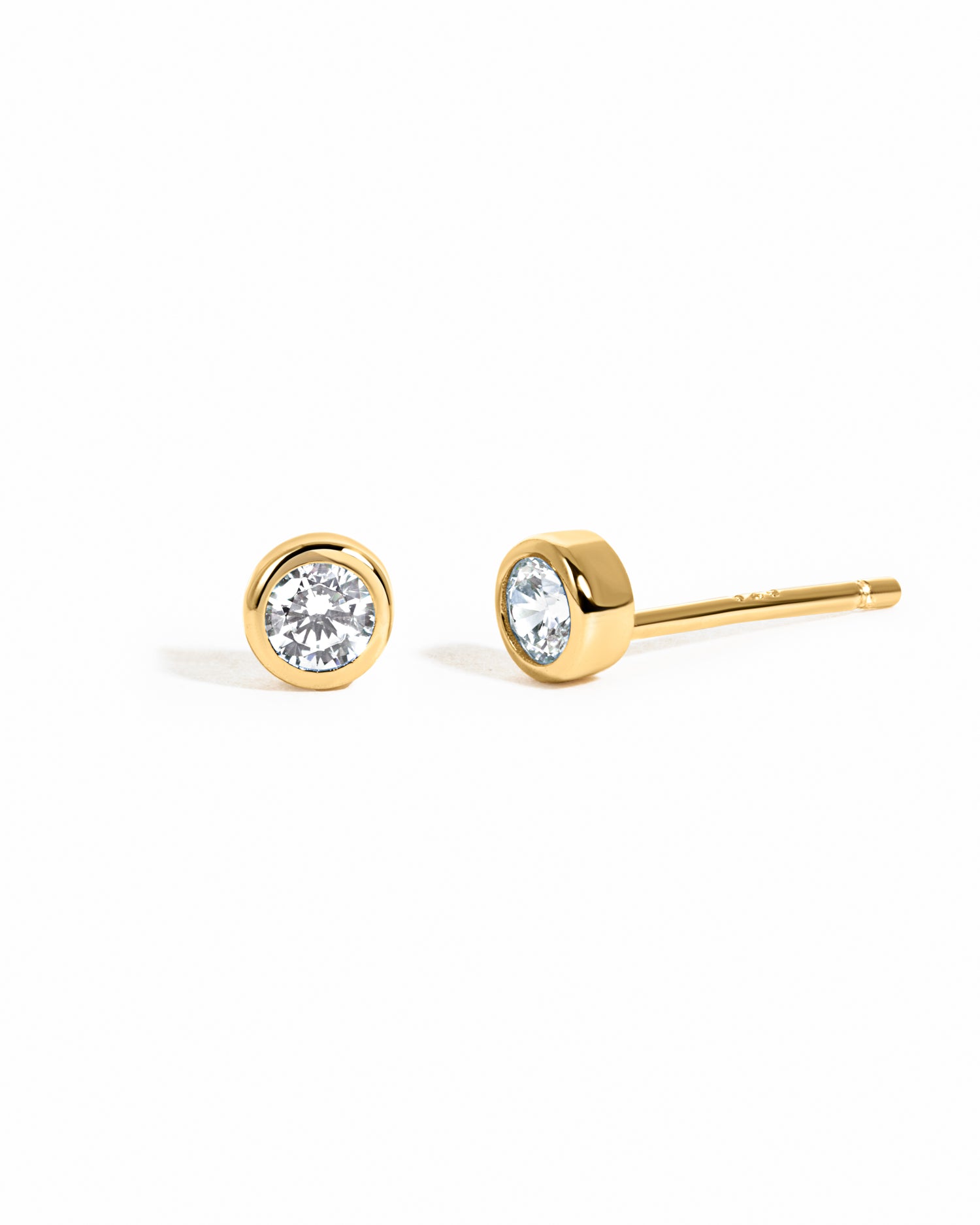 Gold stud earrings with clear gemstones on a white background