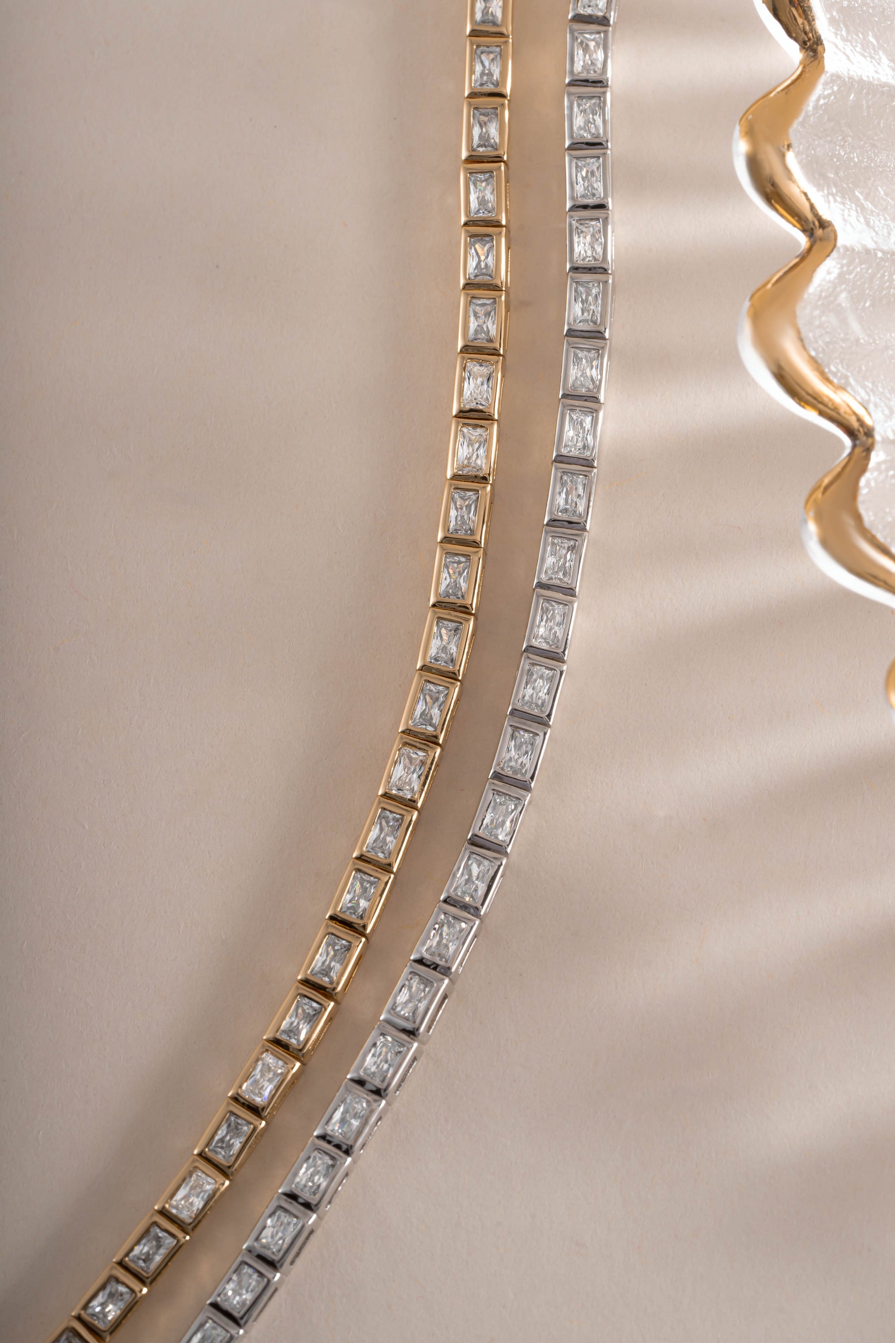 Sami Jewels bezeled baguette tennis bracelet featuring gold and silver tones with sparkling gemstone settings.