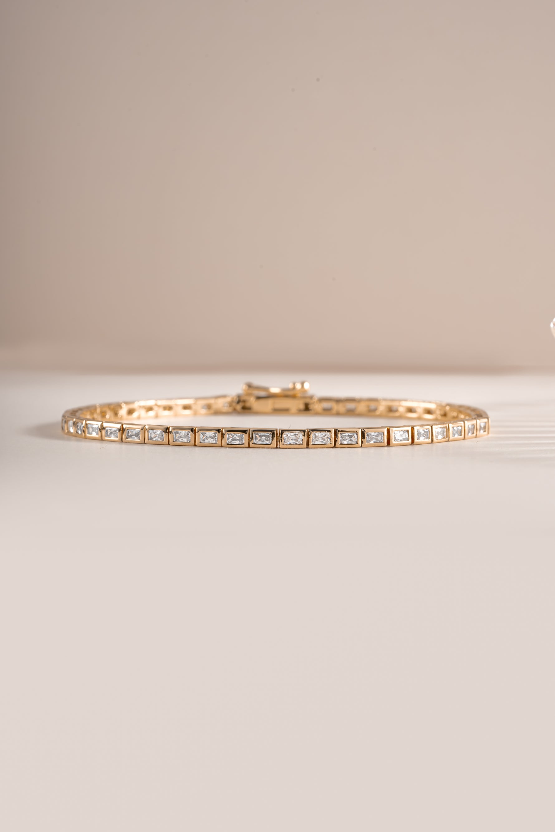 Close-up of Sami Jewels bezeled baguette tennis bracelet in gold, showcasing the elegant rectangular gemstone settings.