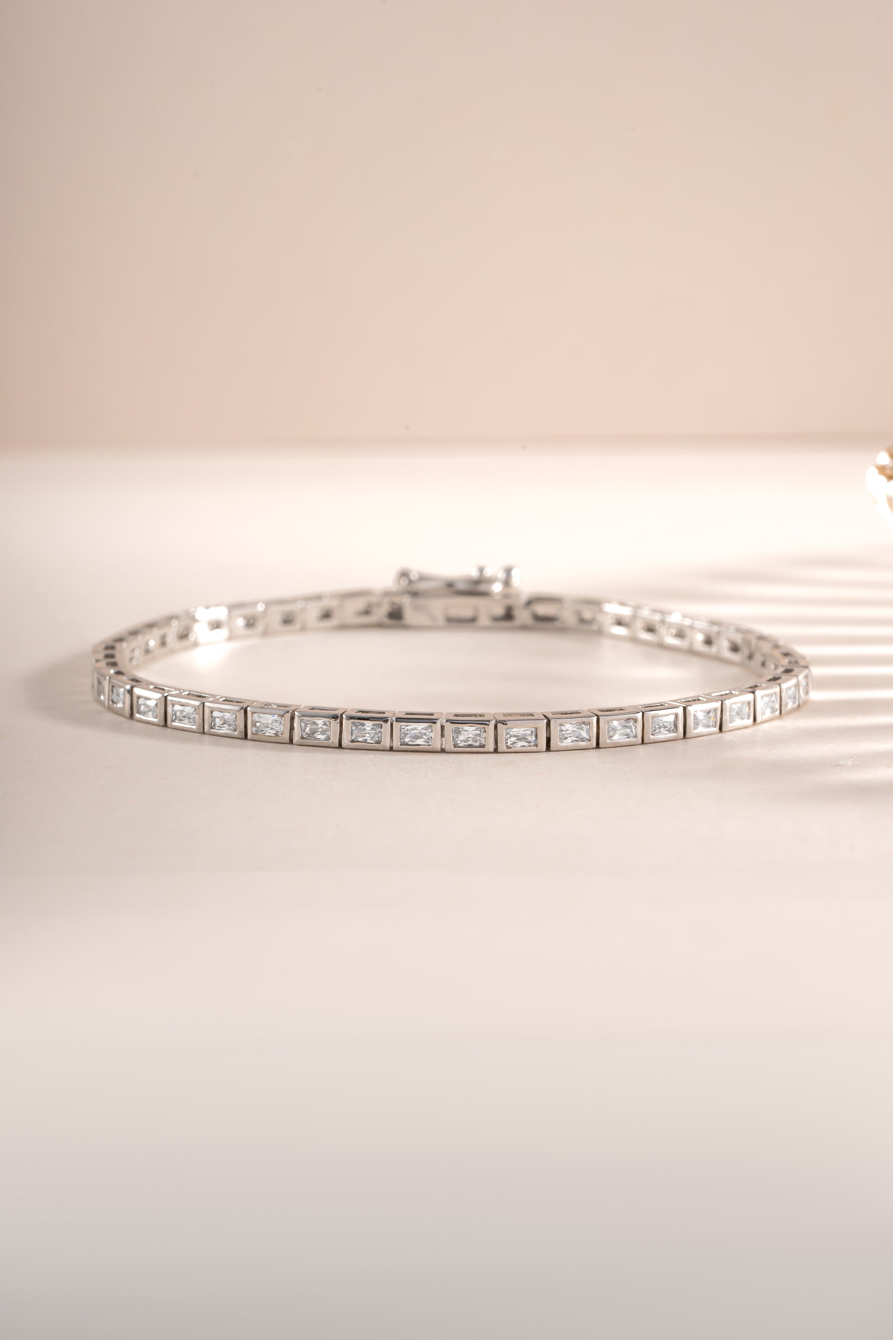 Close-up of Sami Jewels silver bezeled baguette tennis bracelet showcasing sparkling rectangular gemstones and elegant design.