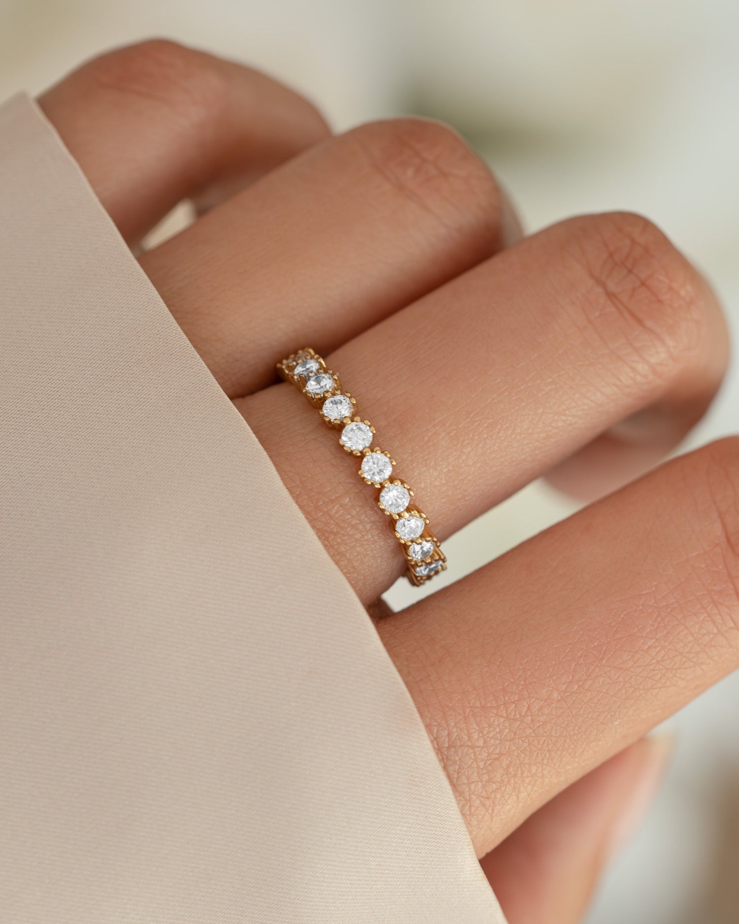 Gold bezeled eternity ring from Sami Jewels featuring a continuous row of sparkling gemstones around the band.