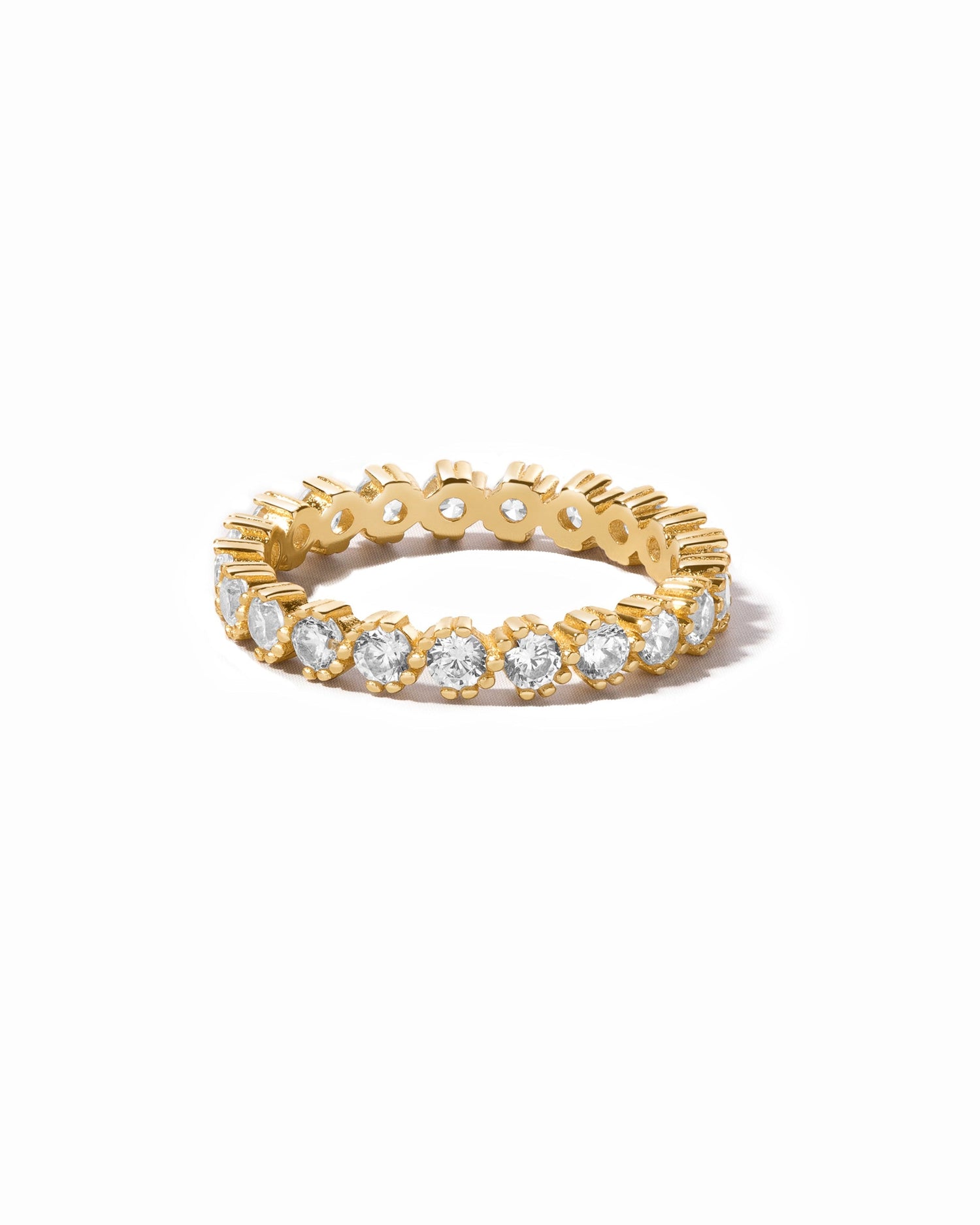 Gold bezeled eternity ring from Sami Jewels with a continuous row of sparkling gemstones on a white background.