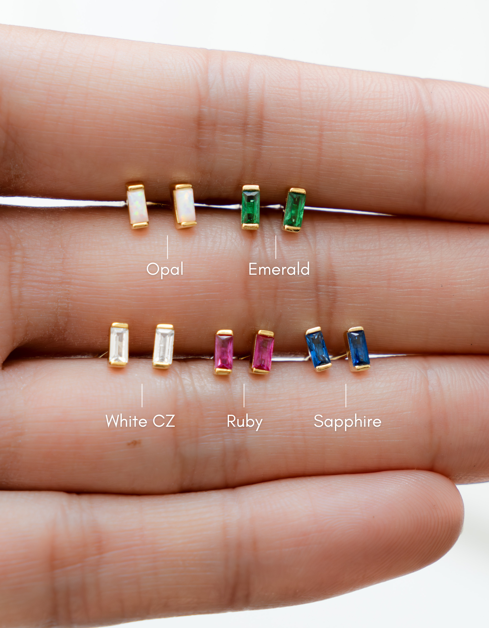 baguette stud earrings on a hand with labels for each stone type.