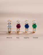 four pairs of three stone huggie hoop earrings in various birthstone colors including ruby, sapphire, emerald and a classic white cz diamond