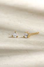 gold diamond solitaire stud earring neutral background