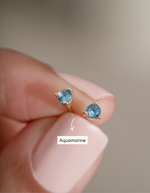 gold aquamarine stud earrings in between fingers