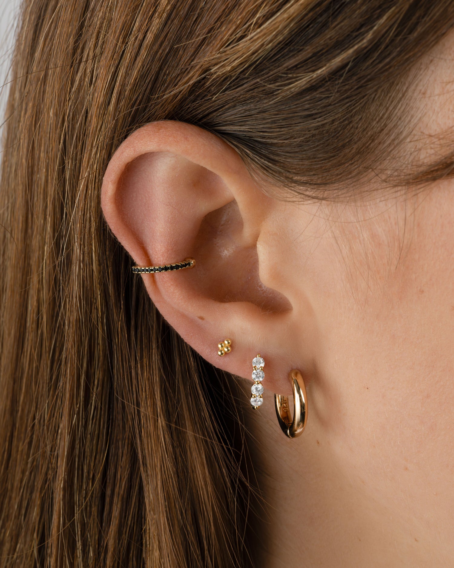 Black CZ ear cuff earrings by Sami Jewels, featuring a sleek gold design on a model.