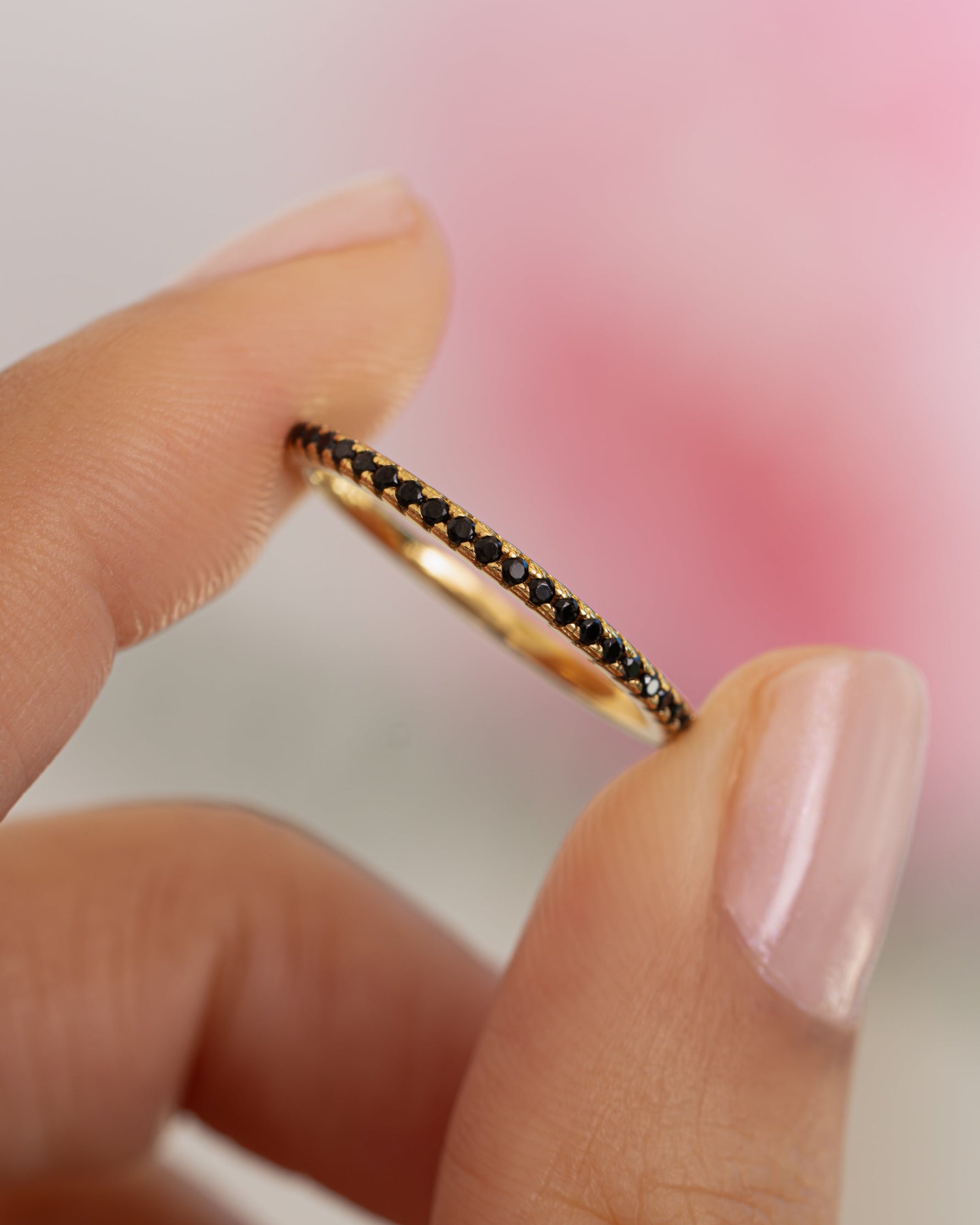 Close-up of Samijewels-527 black CZ eternity ring showcasing sparkling black stones on a gold band.