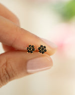 Close-up of Sami Jewels black flower stud earrings showcasing gold accents and intricate floral design.