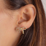 Minimalist bow earrings, worn solo by the model for a chic and feminine look.