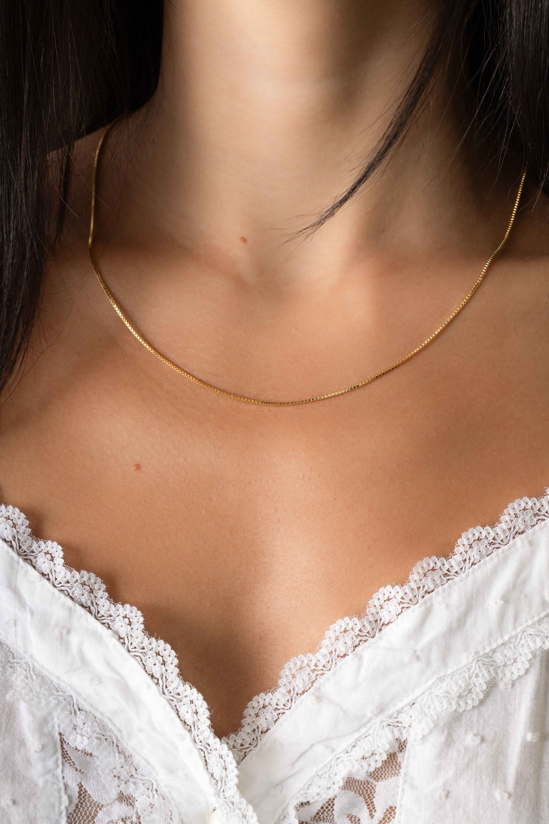 Gold box chain necklace by Sami Jewels, close-up of the elegant, rectangular link design worn by a model.