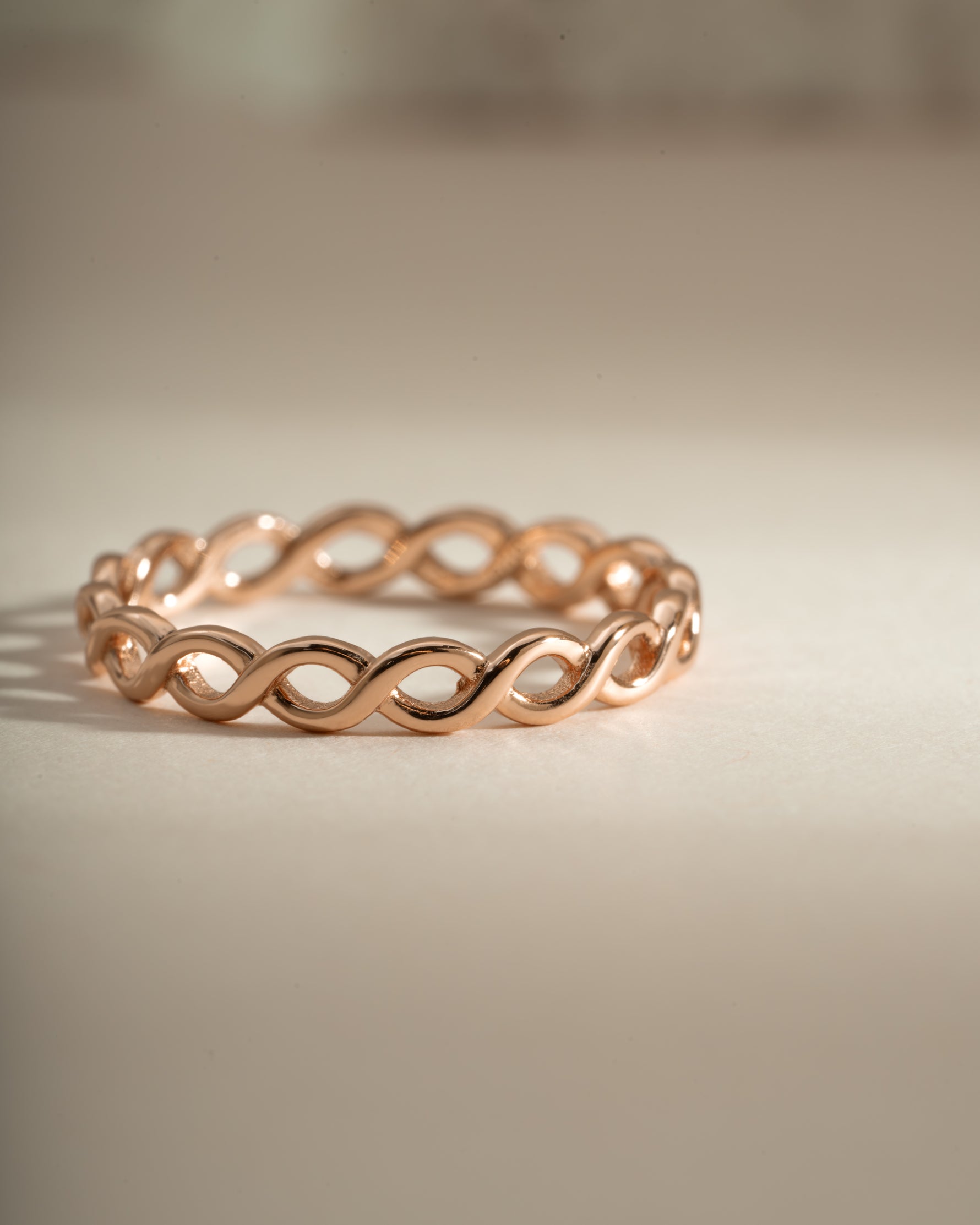 Close-up of Sami Jewels braided eternity ring in rose gold showcasing intricate braided design and polished finish.