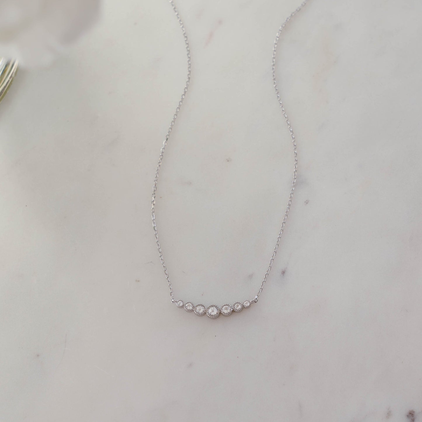 Delicate dainty bridesmaid gift for her, sterling silver diamond bar necklace perfect for weddings and bridesmaids, shown on white marble background. 