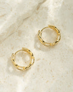 Small chain link hoop earrings by Sami Jewels, showing a close-up profile view of the silver metal hoops with intertwined links.