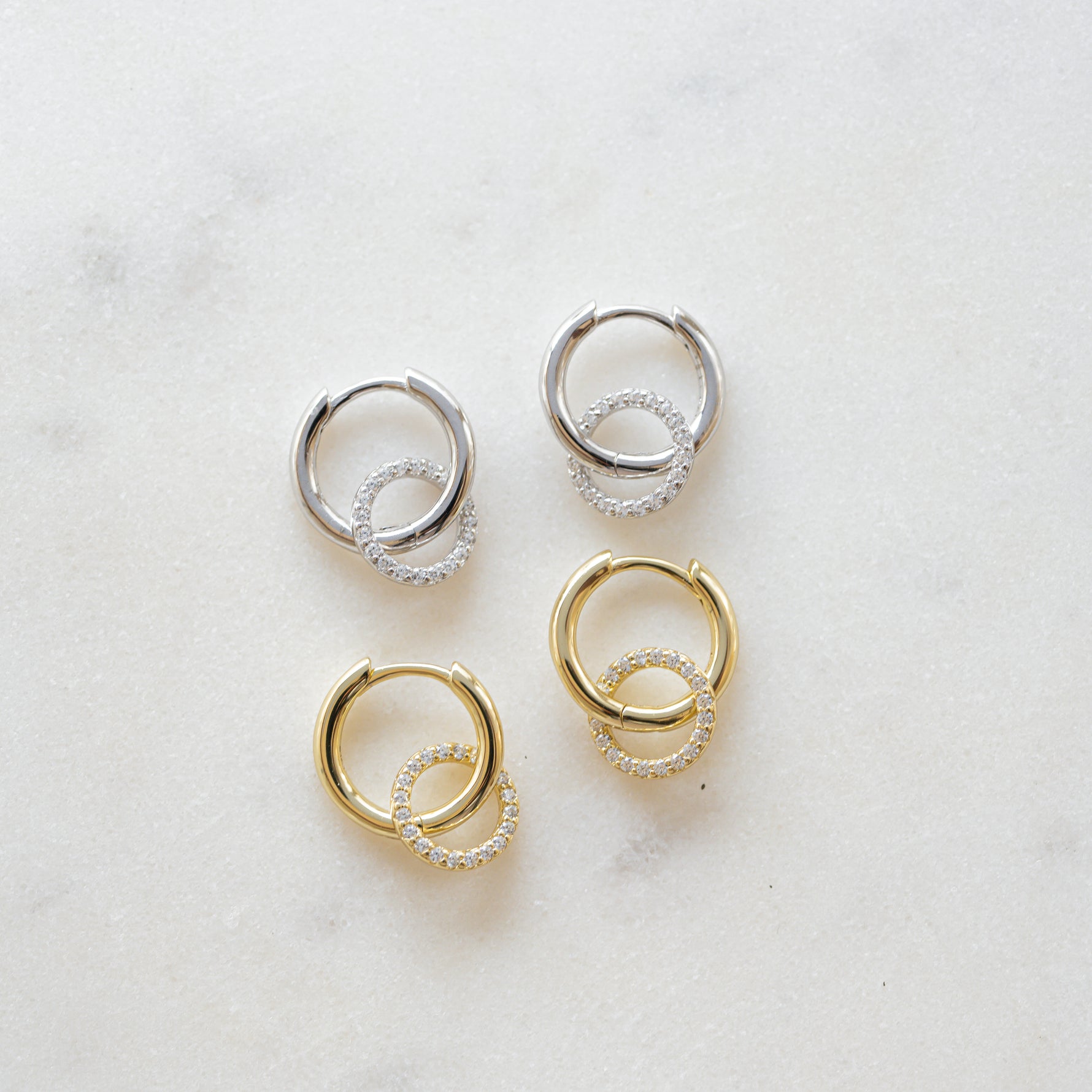 flat lay of lightweight gold and sterling silver hoops with a textured pavé circle charm, adding a subtle touch of sparkle.
