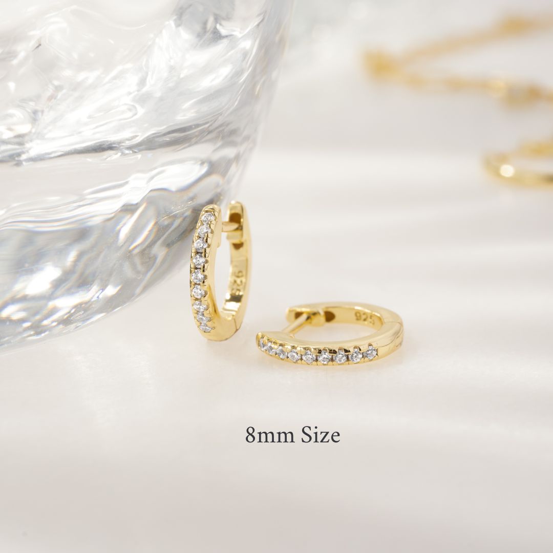 Gold hoop earrings with small diamonds on a white background