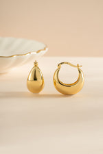 Gold chunky basket tube hoop earrings by Sami Jewels with bold, textured design and thick, rounded hoops.