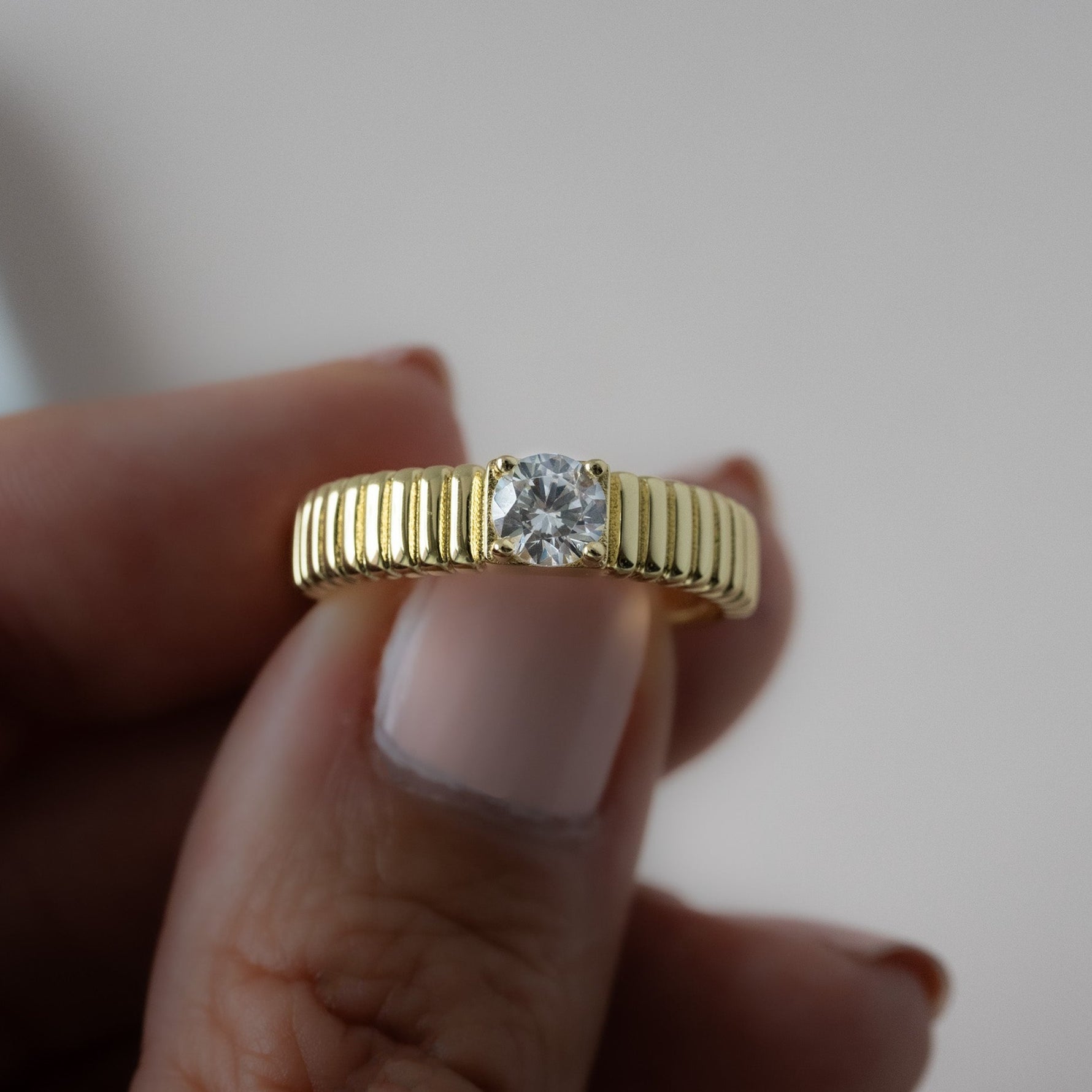 close up of 14k gold ring with its grooved textured surface, that invites the fingertips to explore its raised, rhythmic design.