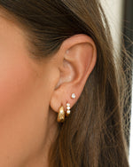 Gold 15mm chunky huggie earrings by Sami Jewels, featuring thick, rounded hoops worn by a model.