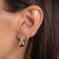 model wearing thick gold hoops with a geometric triangle design on her first piercing, stacked with gold diamond earrings and diamond stud earrings.