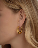 Close-up of Sami Jewels SS Basket Hoops earrings, chunky gold stainless-steel hoops worn by a model.