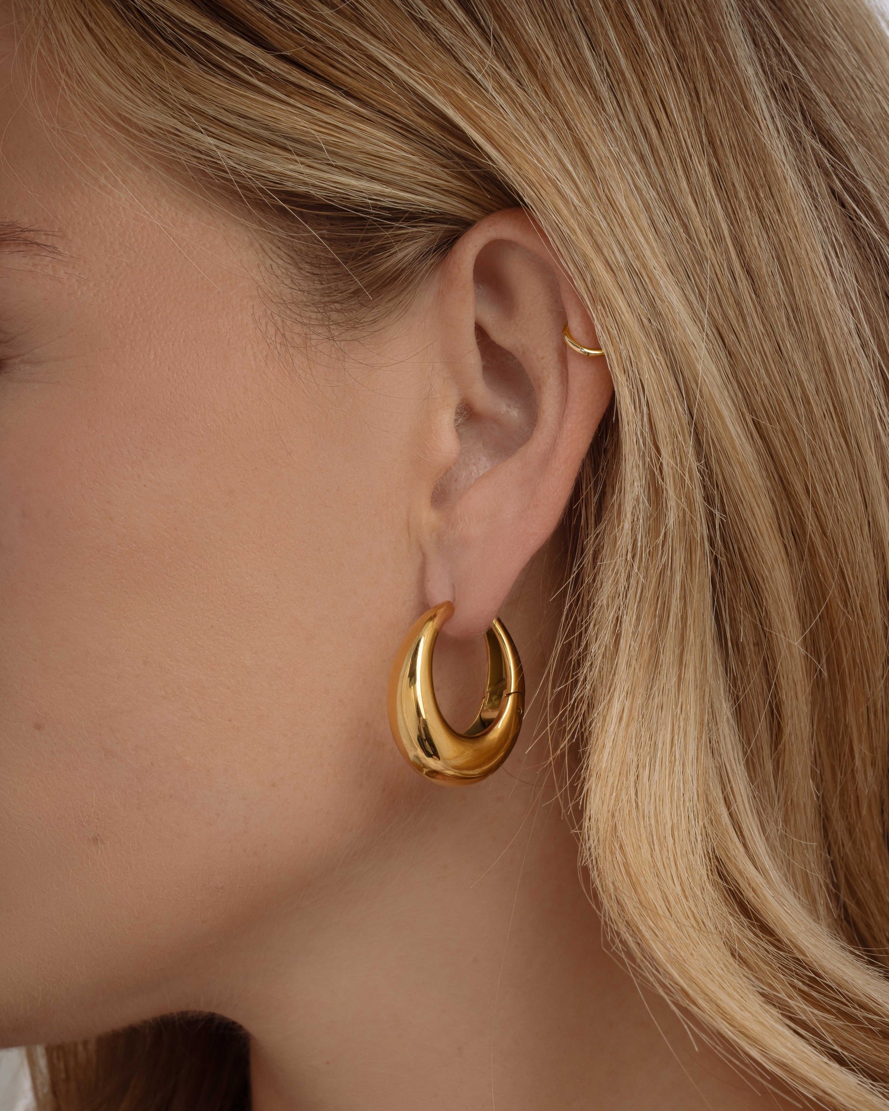 Close-up of Sami Jewels SS Basket Hoops earrings, chunky gold stainless-steel hoops worn by a model.