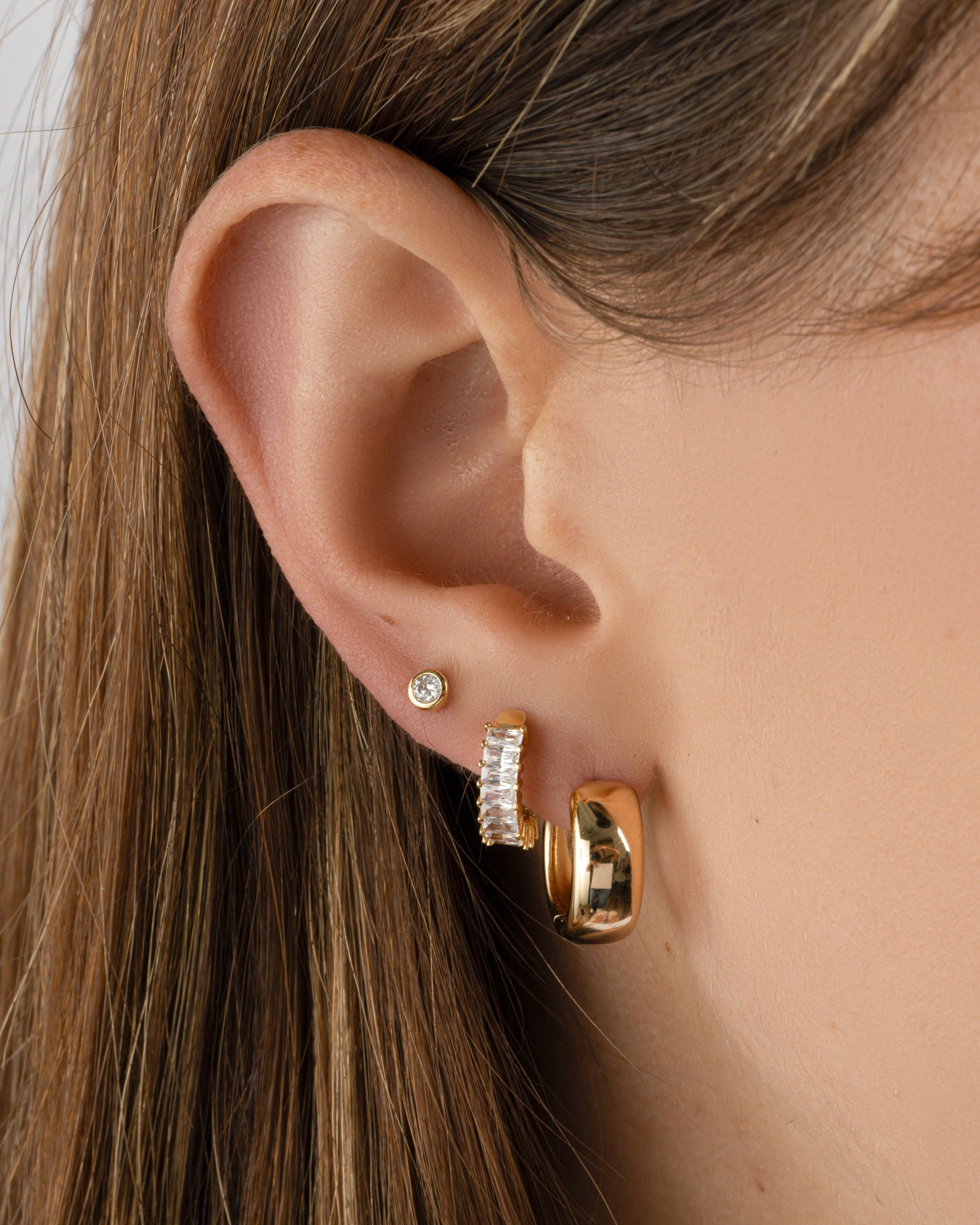 Gold Olivia Hoops earrings by Sami Jewels, chunky huggie hoop design on a model showing their stylish, bold look