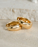 Close-up of gold 15mm chunky huggie hoops earrings by Sami Jewels showing their bold, rounded design and polished finish.