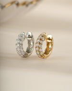 Sterling silver and gold chunky pavé huggie earrings featuring sparkling pave gemstone accents.