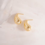 flay lay of a teardrop earrings with a bold sculptural feel, soft, rounded curves of high-shine silver that taper into a silky, weightless drop.