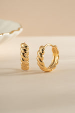 Gold Jacky hoop earrings by Sami Jewels, featuring a croissant-shaped design, shown from an angled view.