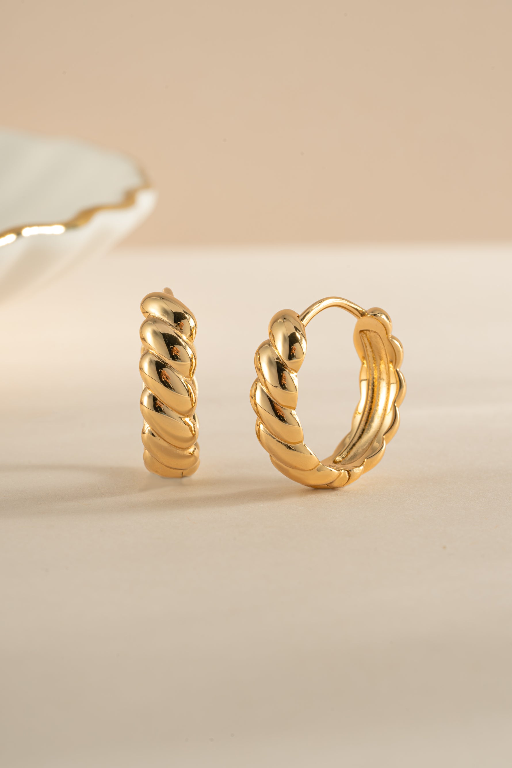 Gold Jacky hoop earrings by Sami Jewels, featuring a croissant-shaped design, shown from an angled view.