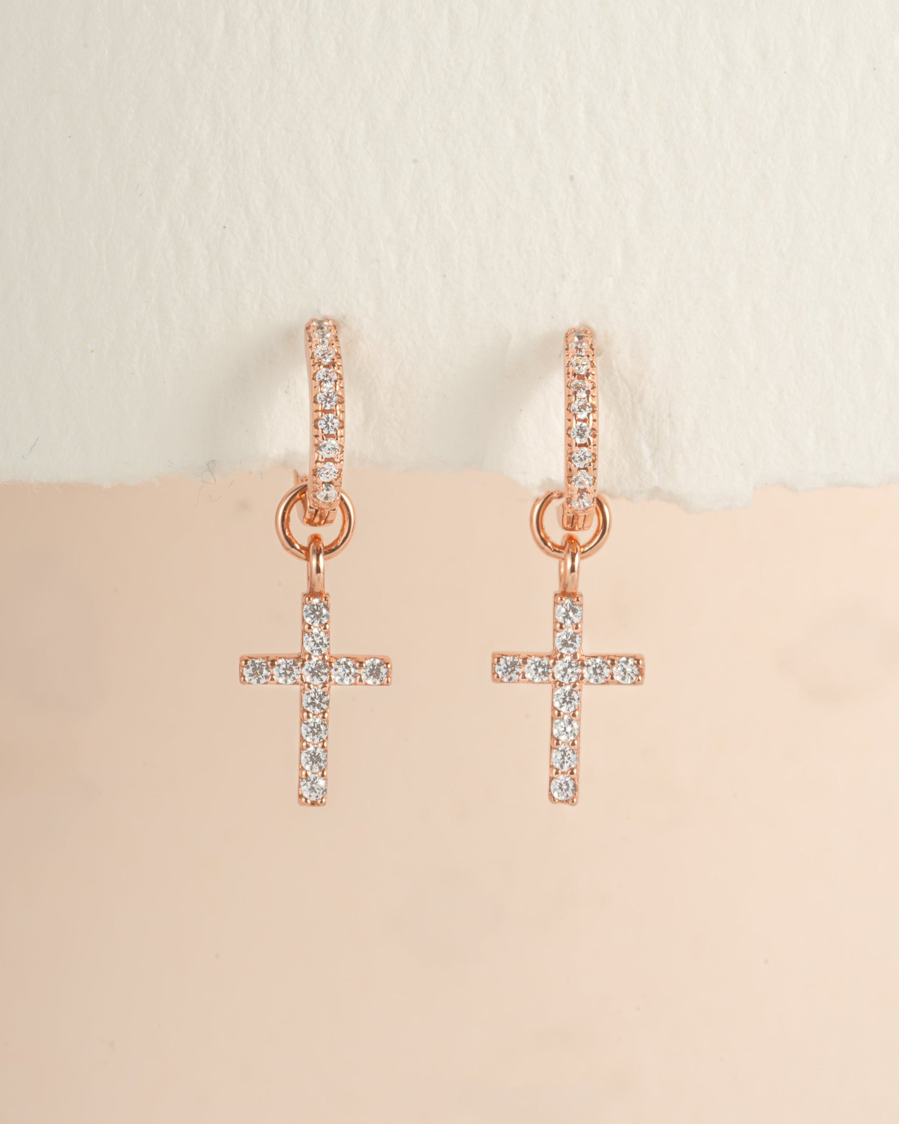 Rose gold CZ cross charm huggie earrings by Sami Jewels, featuring small hoop earrings with cross pendants.