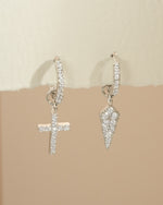 Sterling silver Sami Jewels cross and dagger charm huggie earrings with detailed design and secure hoop closure.