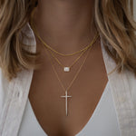 Cubic zirconia halo emerald cut necklace styled on model, with minimalist gold chain necklace and a statement diamond cross pendant necklace, perfect for layering or solo wear